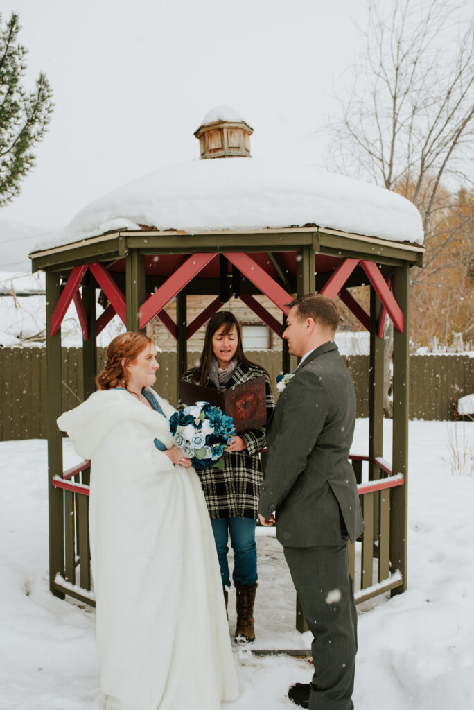 Couple exchanging vows beside snowy creek during intimate Jackson Hole elopement