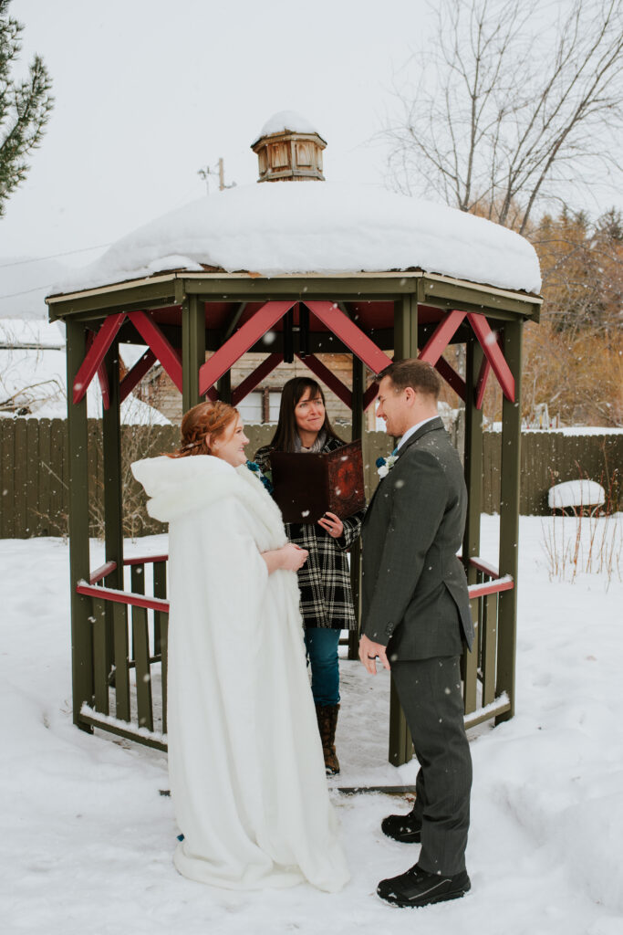 Couple exchanging vows beside snowy creek during intimate Jackson Hole elopement
