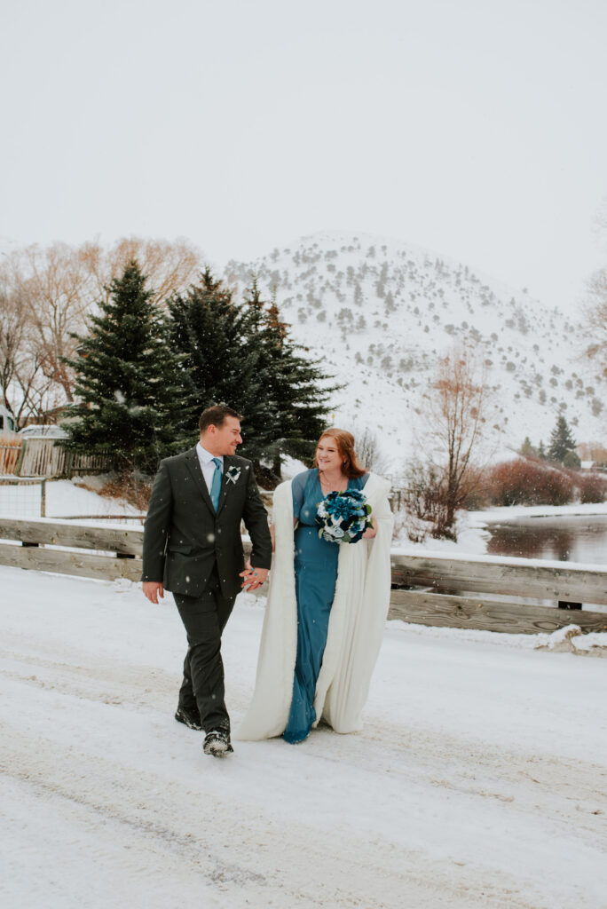 Bride and groom walking hand in hand through snowy downtown Jackson, Wyoming