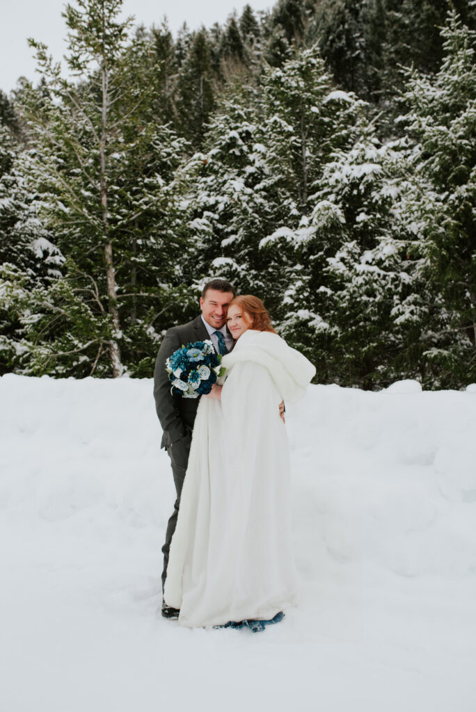 Couple embracing during a winter Jackson Hole elopement with snow-covered Tetons in the background