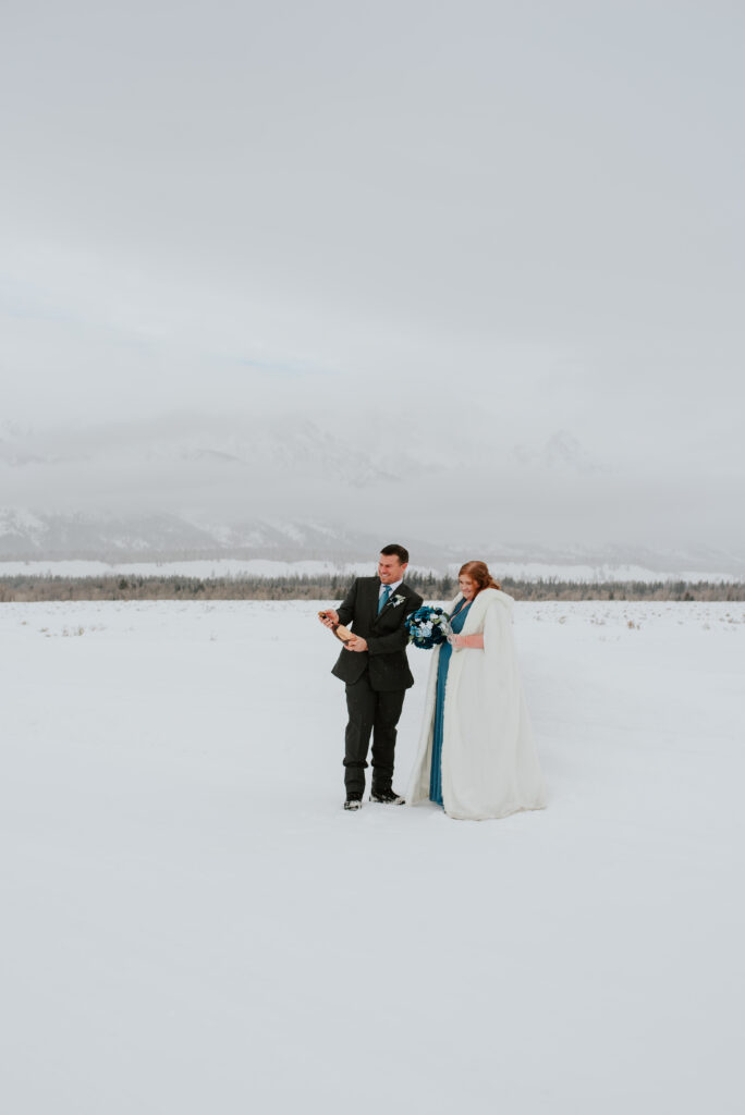 Bride and groom walking through fresh snow during their Tetons winter elopement