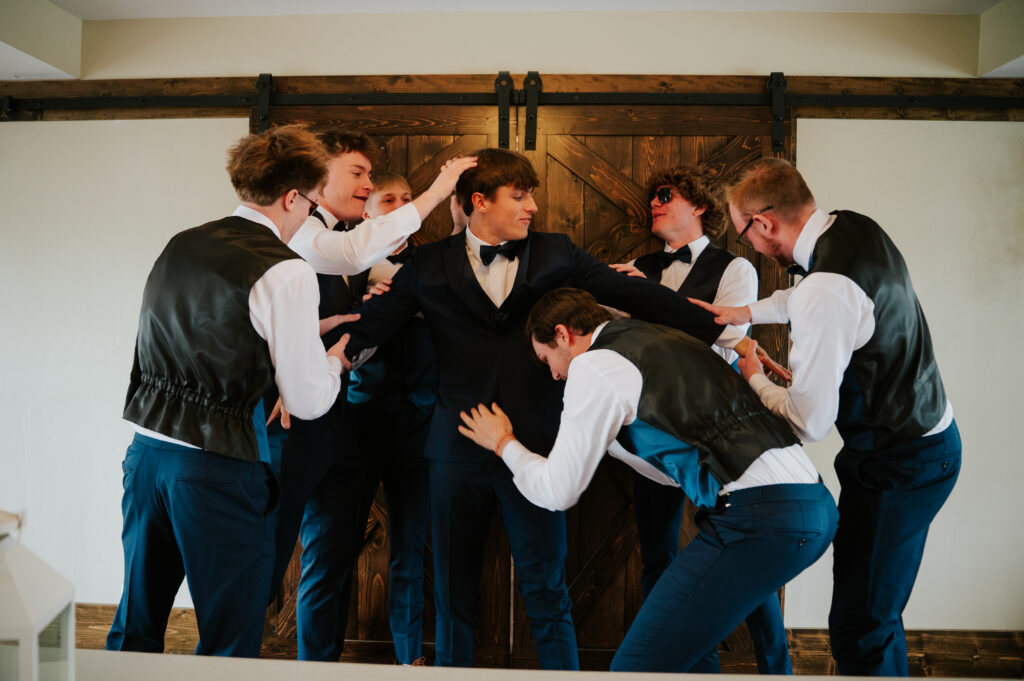 Groom getting ready for a Barn on 1st wedding in Idaho Falls adjusting suit jacket indoors